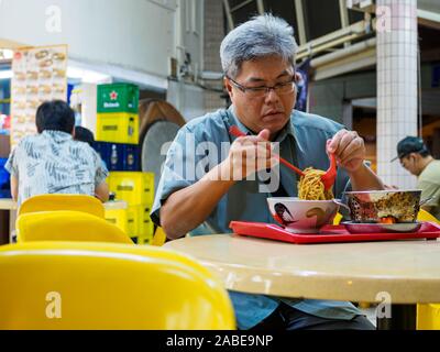 Singapur - 17 Mär 2019 - Eine im mittleren Alter asiatischen Chinses Singaporean Mann genießt eine bis spät in die Nacht Schüssel Nudeln in einem Restaurant/Cafe/das kopitiam/Hawke Stockfoto