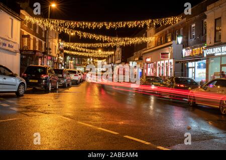 Littlehampton, West Sussex, UK, 26. November 2019, Weihnachtsbeleuchtung und Auto trail Lichter reflektieren auf der nassen Straße. Stockfoto