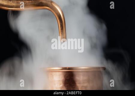 Ein Kupferrohr einer Brennerei mit Dampf. Stockfoto