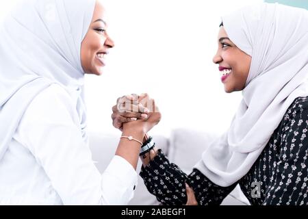 Afrikanische Frau Arm Wrestling Konflikt Konzept, um die Meinungsverschiedenheiten und die Konfrontation mit der traditionellen islamischen hijab Kleidung Stockfoto