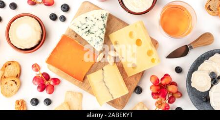 Eine Auswahl an Käse Panorama, geschossen von oben auf einem weißen Hintergrund. Blue Käse, Quark und andere Arten mit Obst und Nüssen, Wein und Trauben Stockfoto