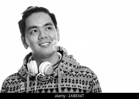 Nachdenkliche junge glücklich asiatischer Mann lächelnd beim Tragen der Kopfhörer um den Hals Stockfoto