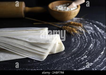 Nahaufnahme des griescreme Teig auf einer bemehlten Tisch. Der dunkle Hintergrund mit Rolling Pin und Ähren. Stockfoto