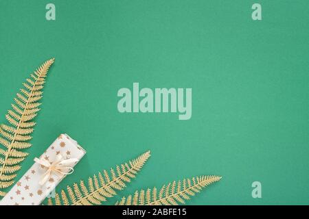 Festliche grüner Hintergrund mit gold Dekoration, Hintergrund mit Glitzer glänzenden goldenen Farnblätter und Geschenkboxen, Flach, Ansicht von oben, kopieren Raum Stockfoto