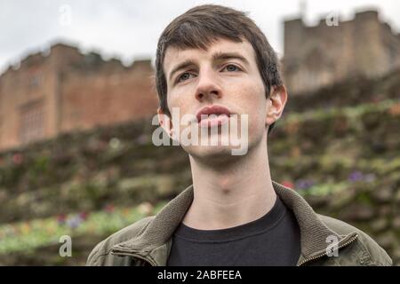 Ein hübscher junger Mann in seinen späten Teens oder Anfang der 20er Jahre steht im Freien und in die Ferne schaut mit einem hoffnungsvollen und nachdenklicher Ausdruck. Stockfoto
