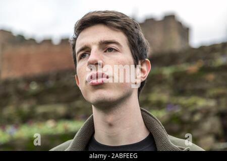 Ein hübscher junger Mann in seinen späten Teens oder Anfang der 20er Jahre steht im Freien und in die Ferne schaut mit einem hoffnungsvollen und nachdenklicher Ausdruck. Stockfoto