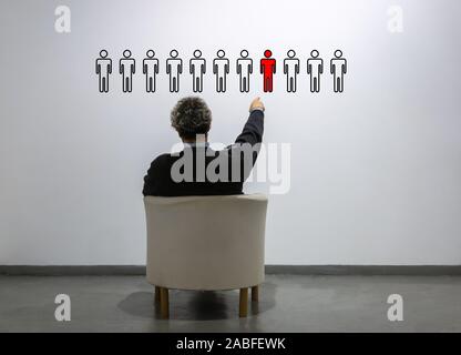 Ein Mann sieht eine Reihe von Personen und wählt eine Person - Konzept der menschlichen Ressourcen, Auswahl, Karriere - Marktsegmentierung Stockfoto