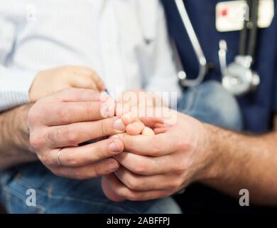 Der Kinderarzt untersucht die Füße des Kindes, der hautarzt behandelt die Fersen, Fuß und Ferse Massage. Konzept der Untersuchung und Behandlung von Kindern Stockfoto