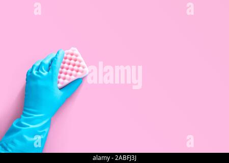 Hand in blau Gummihandschuh Holding rosa Reinigungsschwamm auf rosa Hintergrund mit Kopie Platz für Text oder Logo isoliert Stockfoto