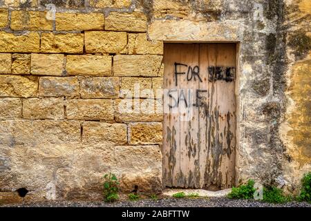 Traditionelle verwitterte und gealterte Kalkstein block Wand mit hölzernen Tür. Teil eines Gebäudes auf der Mittelmeerinsel Gozo, Malta. Stockfoto