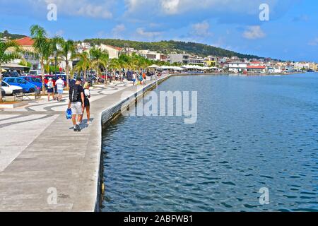 Menschen flanieren entlang der schönen Palmen gesäumten Uferpromenade in der Hauptstadt von Argostoli. Ein beliebter Ort für Schildkröten beobachten. Stockfoto