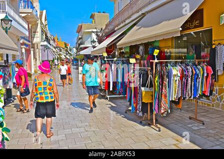 Ein Blick entlang Lithostroto, der wichtigsten Einkaufsstraße im Zentrum der Hauptstadt, Argostoli. Helle und bunte Kleidung auf dem Display. Stockfoto