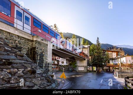 Zermatt, Schweiz - Oktober 7, 2019: Gornergrat rote Bummelzug in der Stadt, die Häuser des Dorfes und Schweizer Alpen Panorama Stockfoto