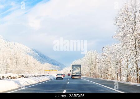 Winter alpine highway road landscape with beautiful white covered snow trees, mountains and blue sky on background at bright cold sunny day. Car trip Stockfoto