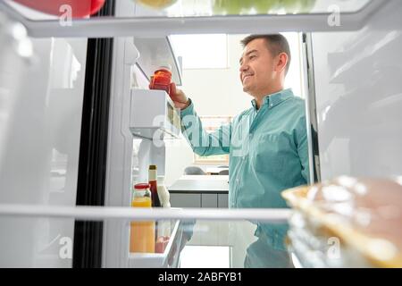 Mann unter Saft aus dem Kühlschrank zu Hause Küche Stockfoto