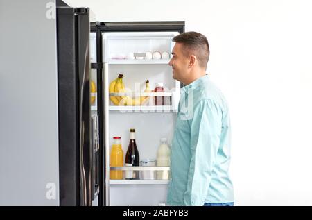 Mann für Lebensmittel im Kühlschrank in der Küche auf der Suche Stockfoto