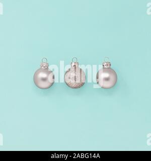 Drei glitzerndes Silber Weihnachtskugeln isoliert auf einem blauen Hintergrund, mit Kopie Raum Stockfoto