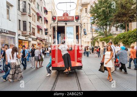 Kind hitching eine Fahrt auf der Rückseite eines alten roten Straßenbahn auf Istiklal Cadessi, Istanbul, Türkei Stockfoto