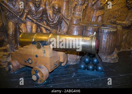 Gun Anzeige eines frühen Canon und kanonenkugeln vor einem Tableau der Schlacht an der Explosion Museum der Naval Feuerkraft; ehemaliger Rüstung Depot der Royal Navy von priddy ist hart, in Gosport. Großbritannien (105) Stockfoto