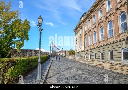 Budapest, Ungarn - Nov 6, 2019: gepflasterten Pfad zusammen mit der Burg von Buda palace Gebäude. Historische Palast, Fassade mit Bogenfenstern. Touristische Attraktion und ungarischen nationalen Erbe. Stockfoto