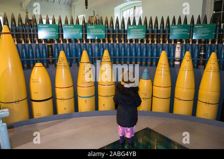 Kind, Mädchen im Alter von 4 Jahren an der Ausstellung von explosiven Granaten, die für die Verwendung durch militärische Kriegsschiffe in ihre Gewehre auf Marineschiffen. Explosion Museum der Naval Feuerkraft; ehemaliger Rüstung Depot der Royal Navy von priddy ist hart, in Gosport. Großbritannien (105) Stockfoto