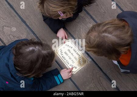 Besucher/Touristen untersuchen die Metall Messingschild auf der Website von HMS Victory an der Stelle, wo Admiral Lord Nelson fiel nach geschossen wird von einem französischen Musketier. Portsmouth. Großbritannien (105) Stockfoto