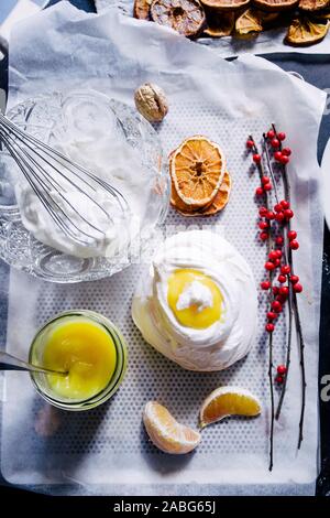 Baiser Nest mit Lemon Quark, mit getrockneten Orangenscheiben auf schwarzem Hintergrund, Ansicht von oben, flatlay Stockfoto