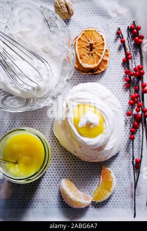 Baiser Nest mit Lemon Quark, mit getrockneten Orangenscheiben auf schwarzem Hintergrund, Ansicht von oben, flatlay Stockfoto