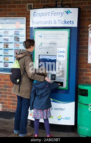 Frau Passagier/Dame mit Kind kaufen Tickets von einem Karten nur automatische ticket Maschine für sich und ihre Tochter zu Portsmouth auf der Gosport Ferry in Hampshire zu reisen. Großbritannien (105) Stockfoto