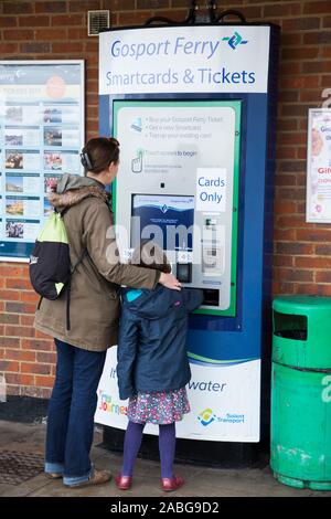 Frau Passagier/Dame mit Kind kaufen Tickets von einem Karten nur automatische ticket Maschine für sich und ihre Tochter zu Portsmouth auf der Gosport Ferry in Hampshire zu reisen. Großbritannien (105) Stockfoto
