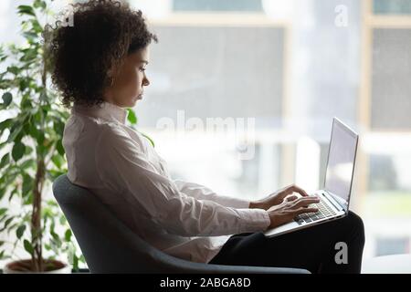 Konzentrierte sich afrikanische amerikanische Frau Arbeiten am Laptop im Büro Stockfoto