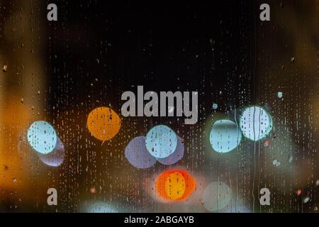 Ein abstrakter Hintergrund der Nacht Straßenlaternen bokeh Durch nasses Glas mit Wassertropfen, close-up mit selektiven Fokus Stockfoto