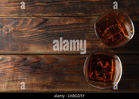 Gläser Whisky mit Eiswürfel auf hölzernen Hintergrund, Ansicht von oben Stockfoto