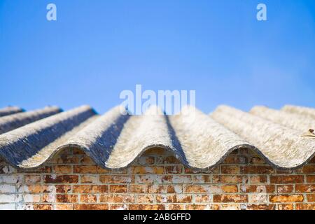 Gefährlich Asbest Dach über eine Mauer - eine der gefährlichsten Materialien in der Bauindustrie sogenannten versteckten Killer. Stockfoto