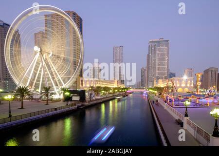 Abends Blick auf Eye of the Emirate Riesenrad und Al Qasba Vergnügungsviertel in Sharjah, Vereinigte Arabische Emirate Stockfoto