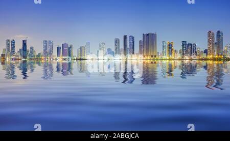 Nacht-Skyline-Blick auf moderne Apartment-Hochhäuser entlang der Corniche in Sharjah, Vereinigte Arabische Emirate Stockfoto