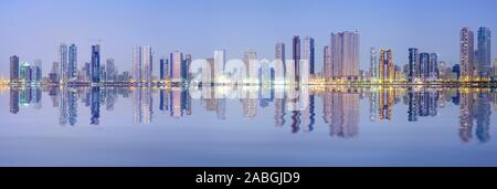 Nacht-Skyline-Blick auf moderne Apartment-Hochhäuser entlang der Corniche in Sharjah, Vereinigte Arabische Emirate Stockfoto