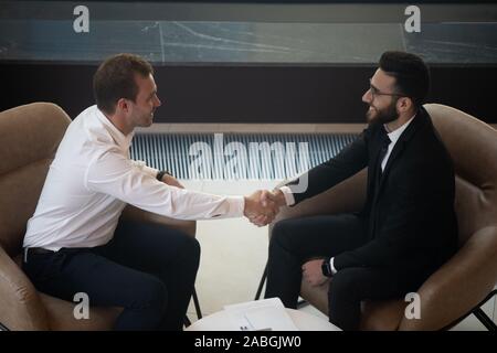 Blick von oben auf die lächelnde multiethnischen Geschäftsleute handshake Begrüßung in der Sitzung Stockfoto