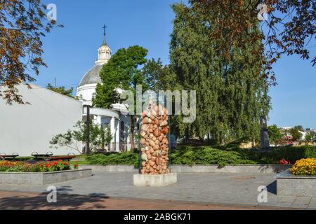 Denkmal in Form einer verglaste Parallelepiped mit Lehm gefüllt Töpfe auf dem Hintergrund der Kirche St. Peter in der lettischen Stadt Daugavpils. Stockfoto