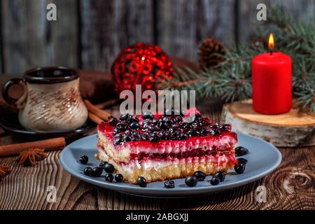 Scheibe Weihnachten Käsekuchen mit schwarzen Johannisbeeren Füllung auf einem rustikalen Holztisch Stockfoto