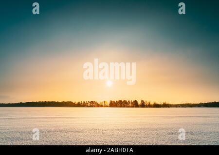 Sonnenuntergang Sonnenaufgang über Feld oder Wiese. Himmel über Winter schneebedeckten Boden. Landschaft unter malerischen Himmel bei Sonnenuntergang Dämmerung Sonnenaufgang. Skyline, Horizont. Stockfoto