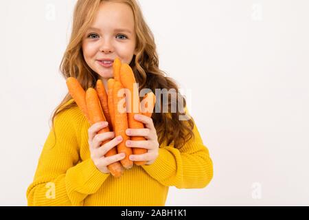 Junge Mädchen, dass Karotten Obst in den Händen auf einem weißen studio Hintergrund. Stockfoto