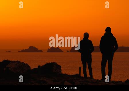 Paar beobachten Klippen an der Pointe de Pen-Hir und Les Tas de Pois sea Stacks gegen Sonnenuntergang, Crozon, Finistère, Bretagne silhouetted, Frankreich Stockfoto
