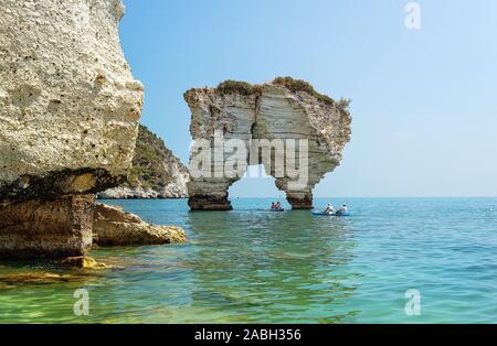 Nicht identifizierbare Touristen mit Kajaks für Faraglioni Di Puglia Baia delle Zagare - berühmte Strand in Italien Stockfoto