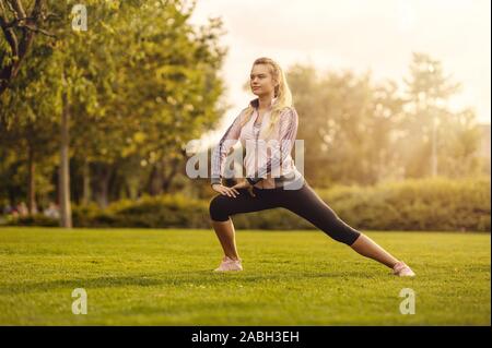 Junge Frau, dehnen und Aufwärmen im Park bei Sonnenuntergang - Attraktive Mädchen vor Fitness im Herbst Park Stockfoto