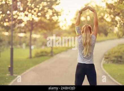 Passen junge Frau im Park - attraktive blonde Frau zu tun Stretching Übungen im Freien - gesunder Lebensstil Konzept Stockfoto