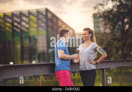 Paar Ausruhen nach Übung im Park - Mann und Frau Training im Freien und Spaß haben nach dem Training bei Sonnenuntergang an einem sonnigen Tag - Sportliche Freunde aft Stockfoto