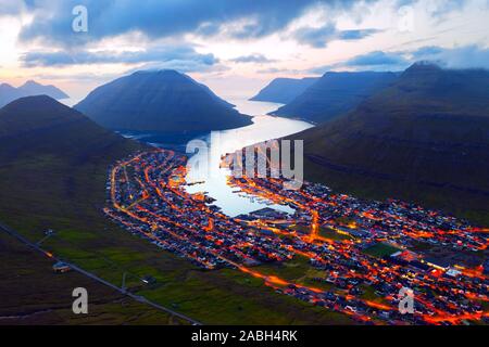 Fantastische Luftaufnahmen abend Stadtbild von klaksvik Stadt mit glühenden Straßen und Fjord, bordoy Island, Färöer, Dänemark. Landschaftsfotografie Stockfoto