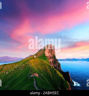 Unglaubliche Sonnenuntergang Landschaft mit kallur Leuchtturm auf grünen Hügeln der Insel Kalsoy, Färöer, Dänemark Stockfoto