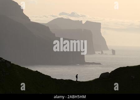 Mann Silhouette am Hintergrund des berühmten risin und Kellingin Felsen und Klippen von Eysturoy und Streymoy Inseln von kalsoy Insel gesehen. Färöer, Dänemark. Landschaftsfotografie Stockfoto